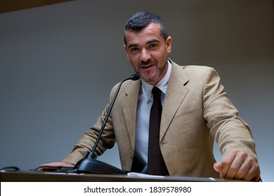 Horizontal waist up portrait of businessman behind with hands on the podium delivering a speech and looking at the camera. - Powered by Shutterstock