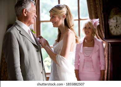 Horizontal waist up profile shot of a bride adjusting her father's jacket smiles at him. - Powered by Shutterstock