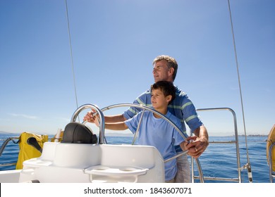 Horizontal waist up shot of a father and son steering a boat on a clear sunny day with copy space.