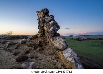 Horizontal wide angle shot of the giant natural rock called Teufelsmauer near Weddersleben, Thale, National Park Harz. Colorful winter sunset light with blue sky. Natural idyllic landscape view.