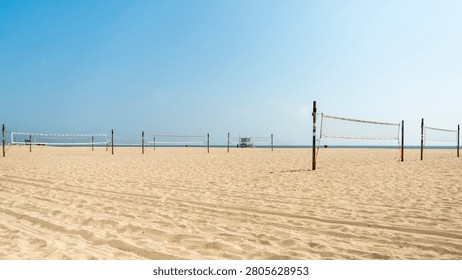 Horizontal wide shot of empty beach volleyball nets set up on the wide sandy shore of Santa Monica Beach in California