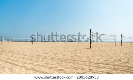 Horizontal wide shot of empty beach volleyball nets set up on the wide sandy shore of Santa Monica Beach in California