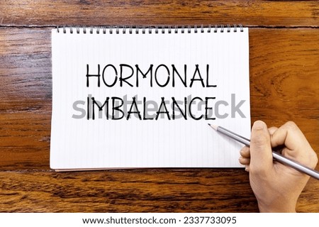 Hormonal imbalance handwriting text on blank notebook paper on wooden table with hand holding pencil. Business concept and legal concept about Hormonal imbalance. [[stock_photo]] © 