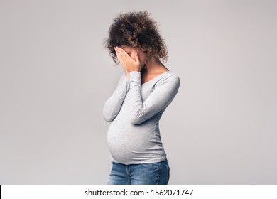 Hormones During Pregnancy. Depressed Expectant Lady Closing Her Face And Crying, Grey Studio Background