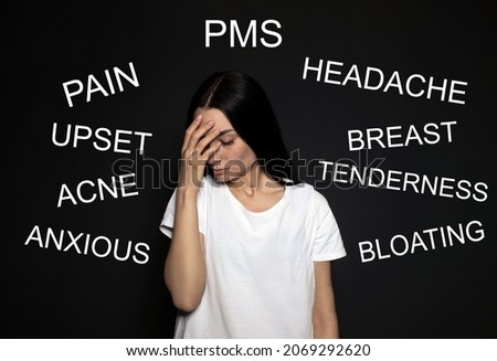 Hormones imbalance. Upset young woman and different words on black background