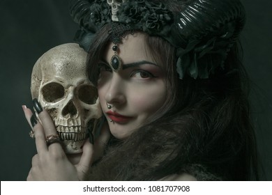 Horned asian cute girl with skull posing over dark background
