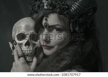 Horned asian cute girl with skull posing over dark background