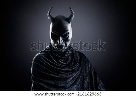 Horned demon at night over dark misty background