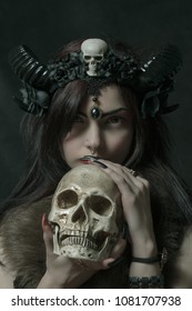 Horned girl posing over dark background with skull