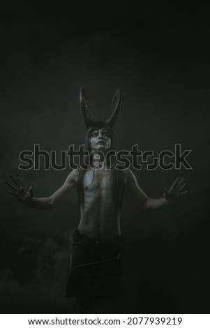Horned young guy posing over black background