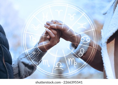 Horoscope compatibility. Loving couple holding hands outdoors and zodiac wheel