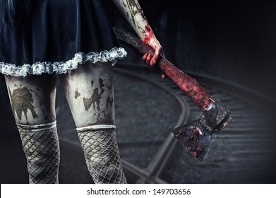 Horror. Dirty woman's hand holding a bloody axe outdoor in night forest