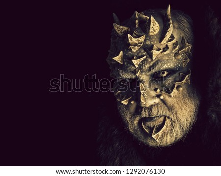 Horror and fantasy concept. Monster with sharp thorns and warts on face. Man with dragon skin and grey beard. Demon head isolated on black. Alien or reptilian makeup, copy space