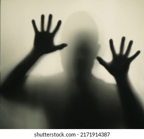 Horror, halloween background - Shadowy figure behind glass of a man - Shutterstock ID 2171914387