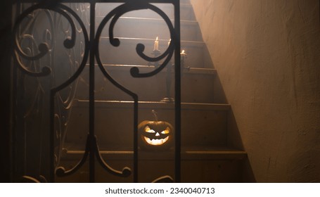 Horror Halloween concept. Creepy abandoned castle. An old candlestick and Halloween pumpkin glowing on wooden stairs with lattice door at night. Decoration with backlight and fog. Selective focus - Powered by Shutterstock