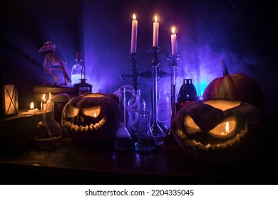  Horror Halloween concept. Magic potions in bottles on wooden table with books and candles. Halloween still-life background with different elements on dark toned foggy background. Selective focus - Shutterstock ID 2204335045