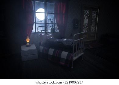 Horror Halloween Concept. A Realistic Dollhouse Bedroom With Furniture And Window At Night. Scared Man In Bed With Fullmoon Outside. Creative Decoration. Selective Focus