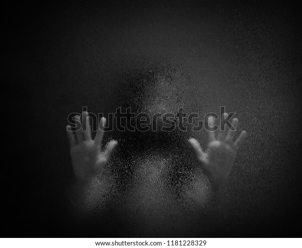 Horror scary shadow of woman behind  glass in black and white. Blurred of  ghost or dead people in darkness. Stressed girl trapped in the room, concept of Halloween or violence against children.