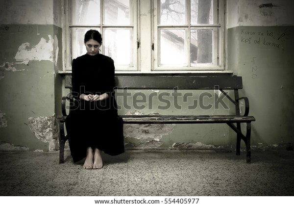 怖い女のホラーシーン 黒いドレスを着た女性が取り壊された部屋のベンチに座っている の写真素材 今すぐ編集