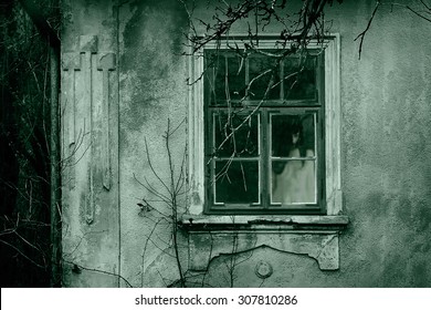 Horror scene of a scary woman. Ghost at the grunge window.