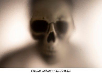 Horror Skeleton Or Grim Reaper Behind The Matte Glass. Halloween Festival Concept.Blurred Picture