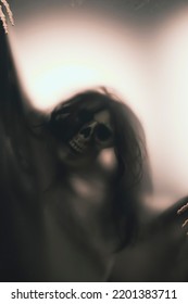 Horror Skeleton Or Grim Reaper Behind The Matte Glass. Halloween Festival Concept.Blurred Picture