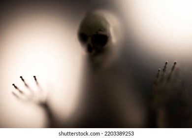 Horror Skeleton Or Grim Reaper Behind The Matte Glass. Halloween Festival Concept.Blurred Picture