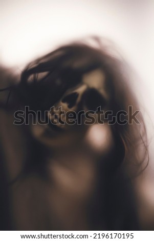 Horror skeleton or grim reaper behind the matte glass. Halloween festival concept.Blurred picture
