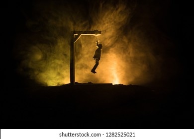 Horror view silhouette of hanged man on scaffold at night with fog and toned light on background. Execution (or suicide) decoration. Horror Halloween concept.