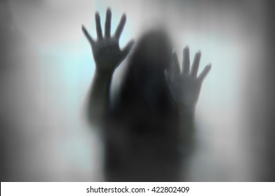 Horror woman behind the matte glass in black and white. Blurry hand and body figure abstraction.