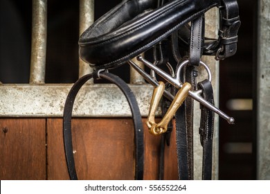 Horse bit and bridle hanging outside a horses stable.