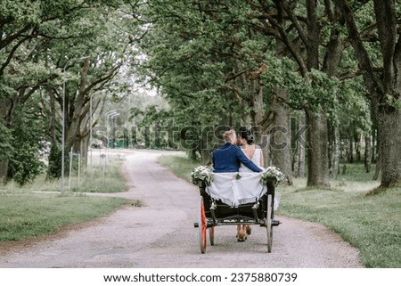 Horse carriage wedding in garden, Newly-wed couple in a black, horse-drawn, open carriage Beautiful sunny day