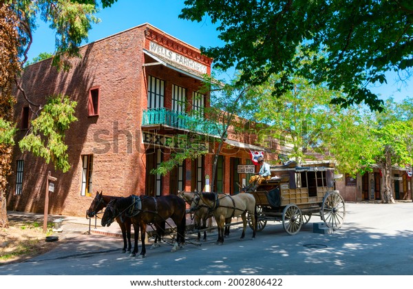 Horse drawn stagecoach ride waits for\
passengers near preserved historic building in Columbia State\
Historic Park - Columbia, California, USA -\
2021