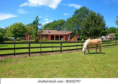 A horse ranch in Washington State, USA with horse standing along the wood fence and the house in the background.
