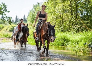 Horse ride, young girls riders, crossing a river, a stream on horseback, splashes from horse hooves, a picturesque place. - Powered by Shutterstock