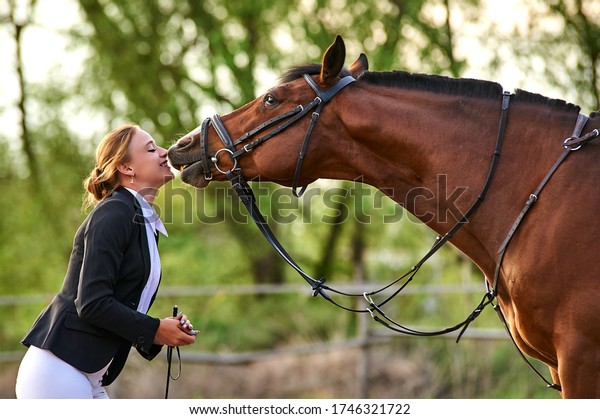 Horse rider girl and horse on a farm. horse kisses
a girl.