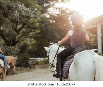 Horse rider.Back view Kids learn to ride a horse.Happy asian kid girl riding horse in horse school farm club.Horseback riding, lovely powerful equestrian.Cowgirl kid fun in farm.Kids Activity.Animals.