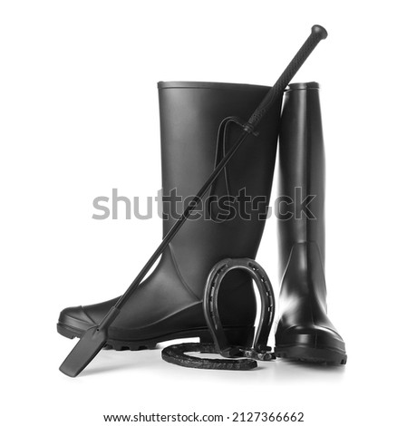 Horse riding boots with crop and horseshoes on white background