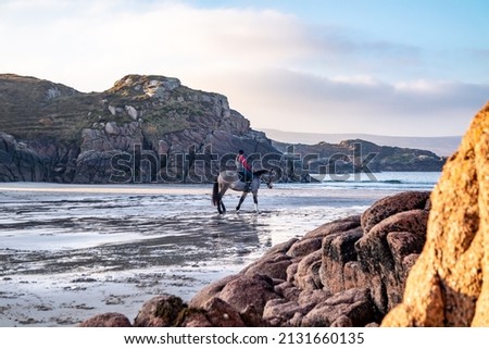 Horse riding at Cloughglass bay and beach by Burtonport in County Donegal - Ireland