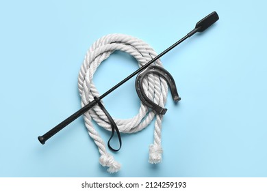 Horse Riding Crop With Rope And Horseshoe On Color Background