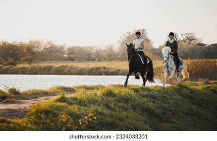 Horse riding, freedom and equestrian with friends in nature on horseback by the lake during a summer morning. Countryside, hobby and female riders outdoor together for travel, fun or adventure - Powered by Shutterstock