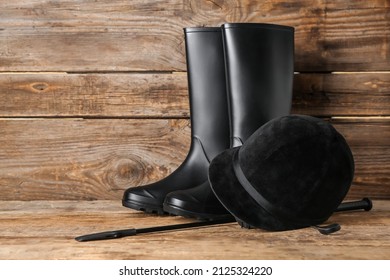 Horse Riding Helmet And Boots With Crop On Wooden Background