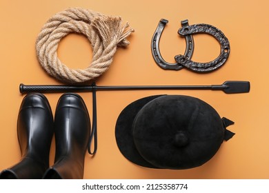 Horse riding helmet, boots and crop with rope and horseshoes on color background