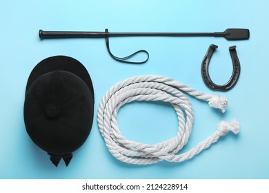 Horse Riding Helmet And Crop With Rope And Horseshoe On Color Background