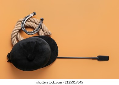 Horse Riding Helmet And Crop With Rope And Horseshoe On Color Background