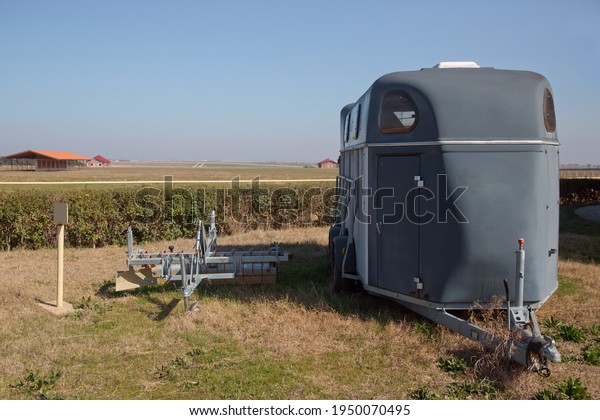 A horse trailer with graphics is ready to hook up\
and go . silver horse trailer on green weadow . A trailer used for\
transporting one adult horse A trailer used for transporting one\
adult horse.