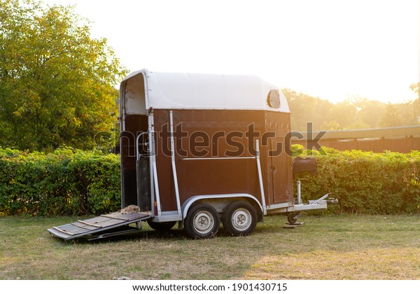 Horse trailer\
standing outdoor with open door. vehicle for horse transportation\
Travel with animals 