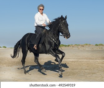 Horse Woman Galloping With Her Black Stallion On The Beach