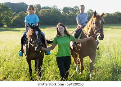 Horseback Riding Lessons - Woman Leading Two Horses With Boys 