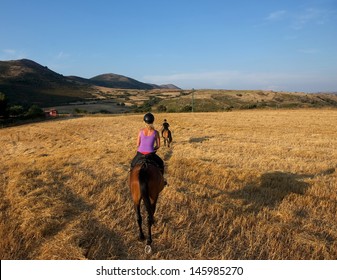 Horseback riding in the mountains at sunset,young woman and man riding a horse bareback during the gold sunset hours, horse riding in Sardinia, Sardinia landscape, Italy, horse riding, horse sport